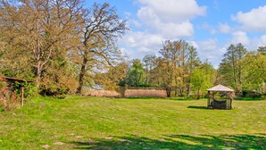 A grassy field with a gazebo and trees.