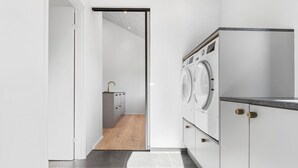 Een moderne wasruimte met een wasmachine, droger en een klein wasgedeelte.