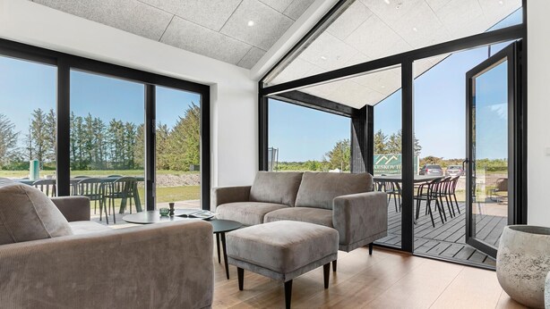 Een moderne woonkamer met een grote glazen deur die uitkomt op een terras.
