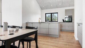 Een moderne keuken met witte kastjes, een zwart aanrecht en een raam met uitzicht op bomen.