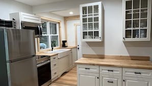 Eine moderne Küche mit Edelstahlgeräten, weißen Schränken und Holzböden.