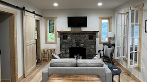 Ein geräumiges Wohnzimmer mit Kamin aus Stein, einem großen Sofa und einer hölzernen Bank.