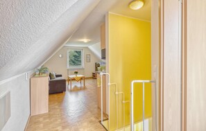 Un interior moderno con suelo de madera, una pared de acento amarilla y un techo estilo loft.