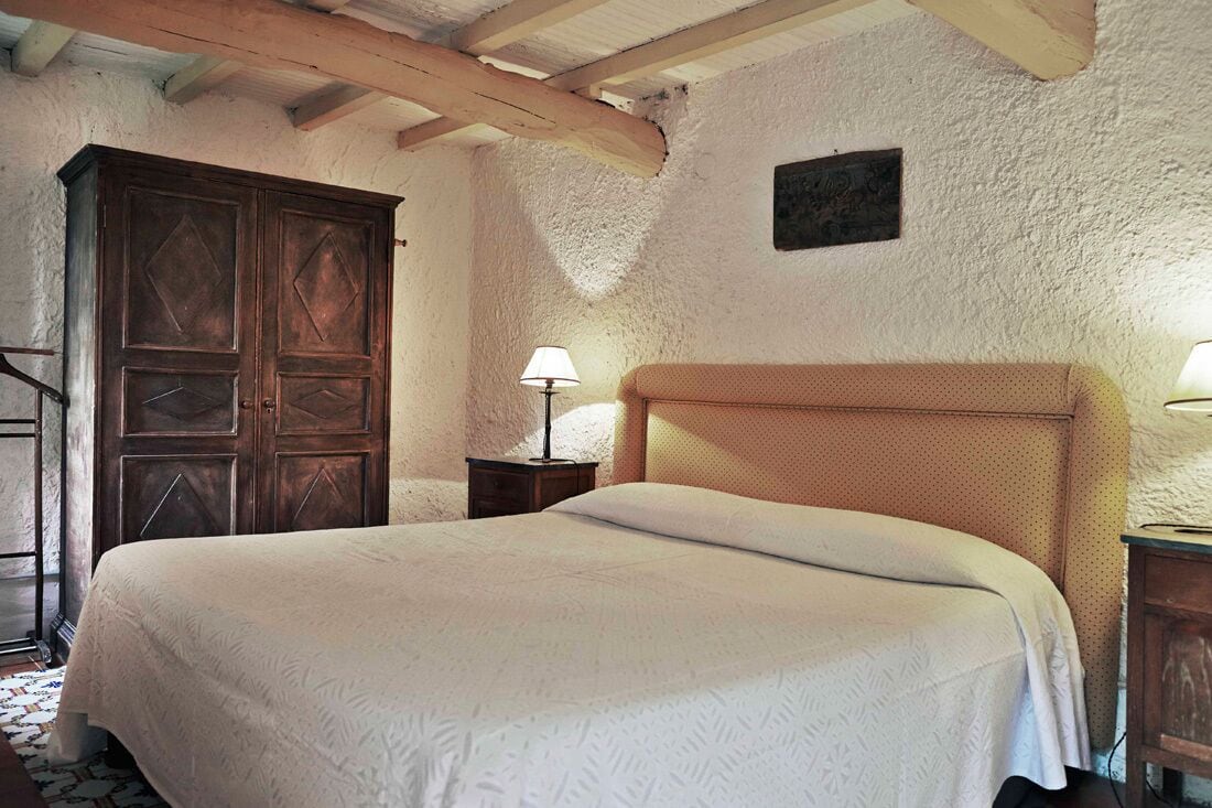 Une chambre à coucher avec un grand lit, une armoire en bois et une petite table de chevet avec une lampe.