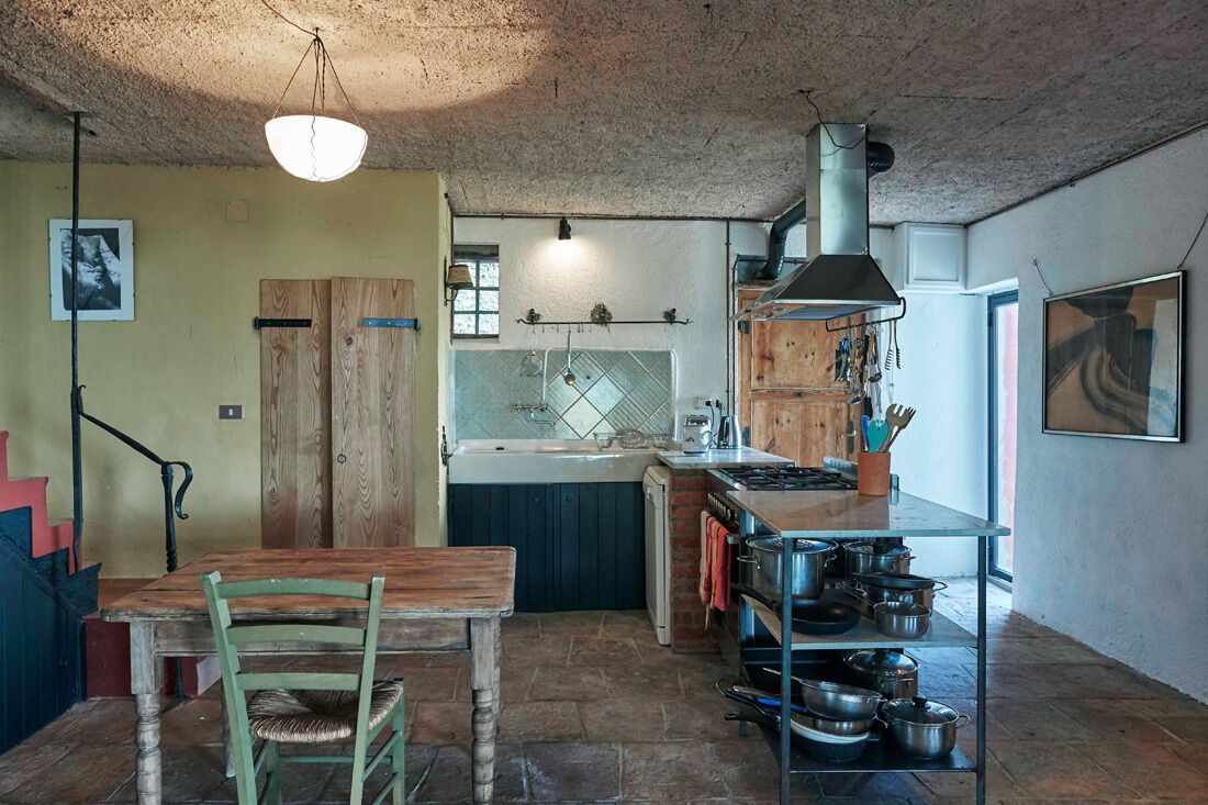 A rustic kitchen with a wooden table and chairs, a sink, and a stove.
