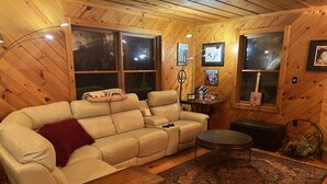 Uma sala de estar aconchegante com um sofá de couro bege, uma mesinha de madeira e um tapete estampado.