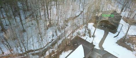 Une cabane entourée d’une forêt, et la neige recouvre le sol.