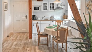 A kitchen with white cabinets, a dining table with green placemats, and a wooden ceiling.