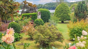 A well-maintained garden with various shrubs, flowers, and a stone structure.