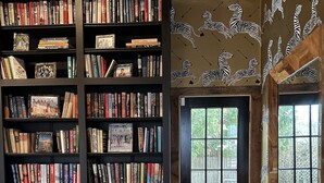 A cozy reading nook with a large bookshelf, a comfortable couch, and a view of the outdoors through a glass door.
