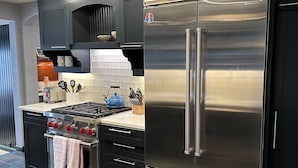 A modern kitchen with a stainless steel refrigerator, a gas stove, and dark cabinetry.