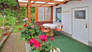 A covered patio area with a table and chairs, a door, and a window. - Ferienhaus Waren (Müritz) (Waren (Müritz) OT Ware)