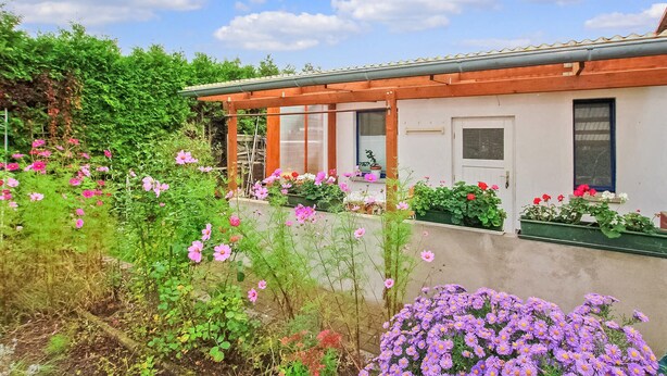 A building with a garden area featuring various flowers and plants. - Ferienhaus Waren (Müritz) (Waren (Müritz) OT Ware)