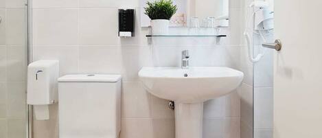 A modern bathroom with a toilet, sink, and glass shower enclosure.