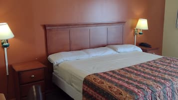 A hotel room with a large bed, two bedside lamps, a wooden nightstand, a desk, and a chair.