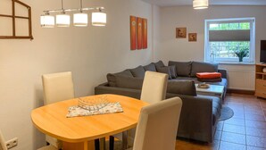 Una sala moderna con una mesa de comedor de madera, un sofá gris y una ventana con persianas.