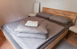 Un lit bien fait, avec une couvre-lit à motifs, deux oreillers et une couverture pliée.