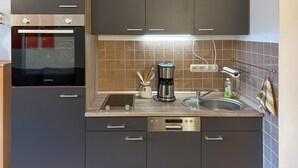 Una cocina moderna con horno empotrado, cafetera, fregadero y lavavajillas.