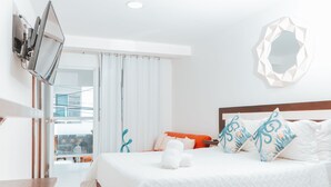 A hotel room with a bed, a TV mounted on the wall, a balcony with a view, and a decorative mirror on the wall. - BEIRUT INN (San Andrés)