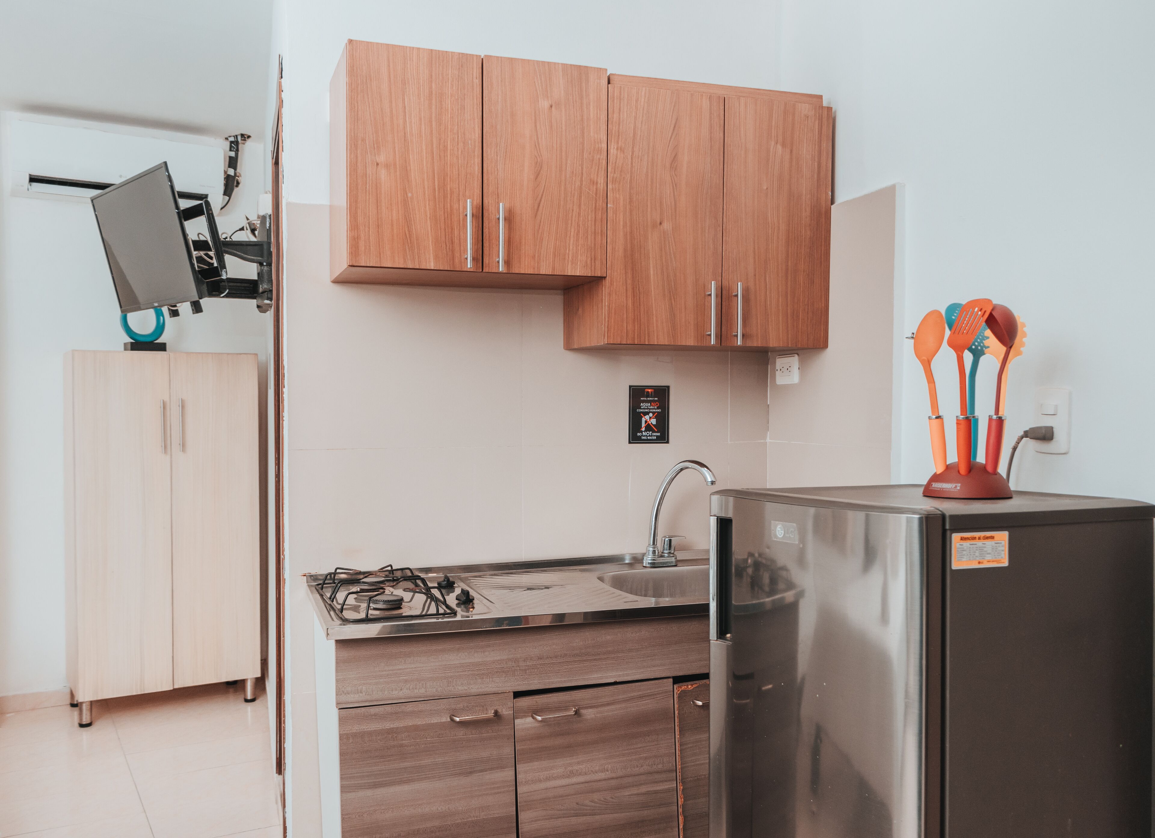 Una cocina moderna con armarios de madera, un refrigerador de acero inoxidable, una estufa a gas y un lavamanos.
