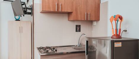 Una cocina moderna con armarios de madera, un refrigerador de acero inoxidable, una estufa a gas y un lavamanos.