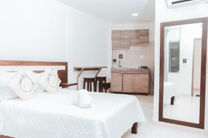 Una habitación de hotel con cama, kitchenette pequeña y baño.