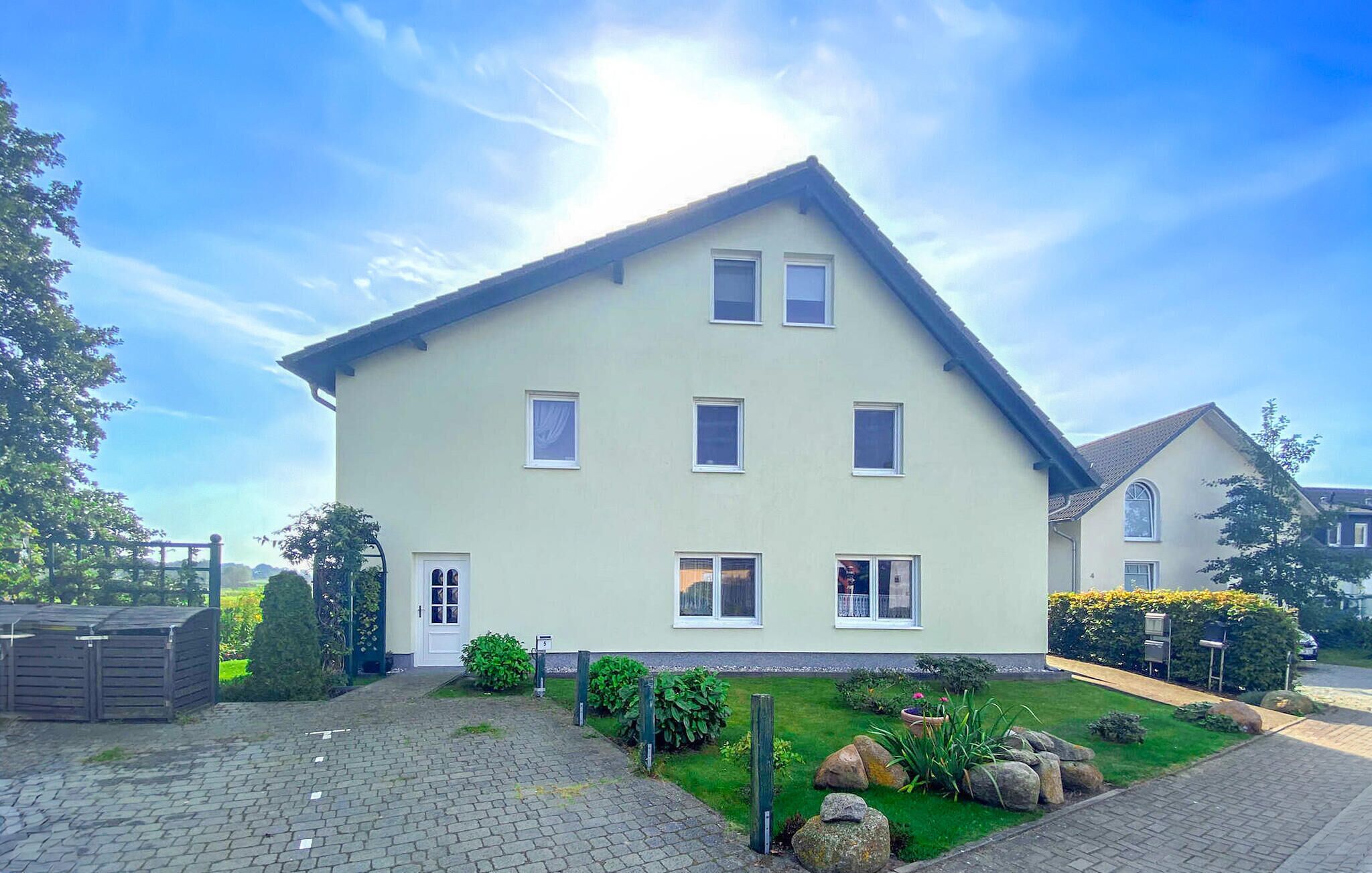 Ein zweigeschossiges Haus mit geneigtem Dach, mehreren Fenstern und einer Haustür.