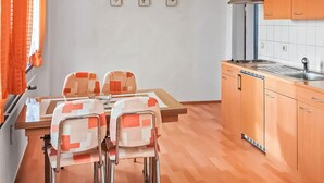 Una cocina compacta con una mesa y sillas, estufa y lavamanos.
