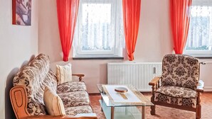 Una sala de estar con sofá, sillón y una mesa de centro de vidrio.