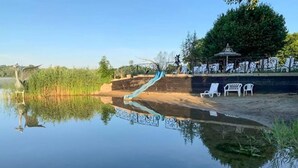 Ein ruhiger See mit Spiegelung, eine kleine Brücke und ein Pavillon mit Bänken.