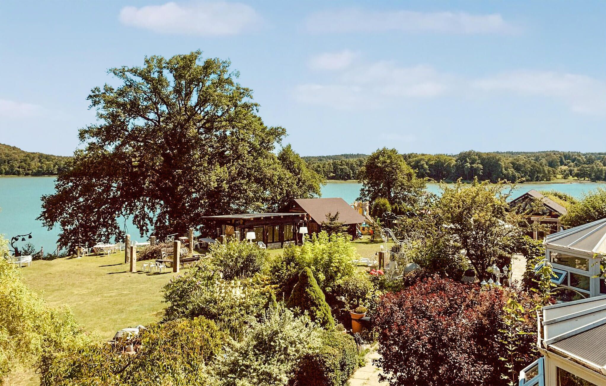 Une propriété située au bord d’un lac, avec un grand arbre, un chalet en bois et un belvédère.