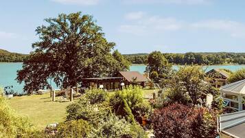 Une propriété située au bord d’un lac, avec un grand arbre, un chalet en bois et un belvédère.