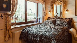 Ein Schlafzimmer mit einem großen Bett, einem Fenster mit Vorhängen, einer Wanduhr und einem Spiegel mit dekorativem Rahmen.