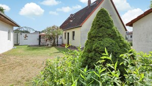A residential property with a well-maintained lawn, a coniferous tree, and a white building with a red roof. - Ferienwohnung Wesenberg (Wesenberg OT Strasen)
