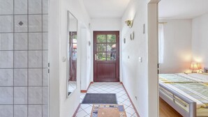 A narrow hallway with a wooden door, a mirror, and a bed with a bedside table and lamp. - Ferienwohnung Wesenberg (Wesenberg OT Strasen)