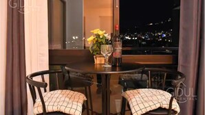 A dining table with two chairs, a bottle of wine, and a vase with flowers.