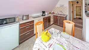 A compact kitchen with a microwave, coffee maker, and sink. There is a dining table with a coffee-themed tablecloth and a yellow bag on it. - Ferienwohnung Neukloster (Neukloster)