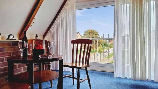 A dining area with a table and chairs, a bottle of wine, and a glass on the table. - Ferienwohnung Neukloster (Neukloster)