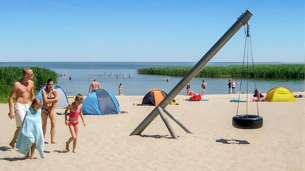A beach with tents and a swing set. - Ferienhaus Ueckermünde Bellin (Ueckermünde OT Bellin)