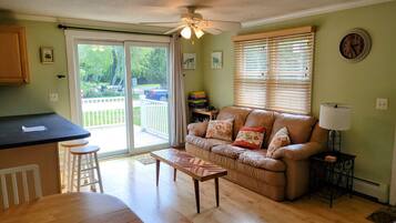 A living room with a sofa, a coffee table, a dining table, and a kitchen area with a counter.