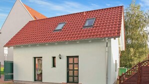 Un bâtiment d’un seul étage, avec un toit recouvert de tuiles rouges, deux fenêtres et une porte verte.