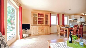 Un vaste espace de vie comprenant un meuble en bois, un téléviseur et une table à manger avec des chaises.