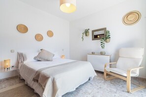 Une chambre à coucher comprenant un lit, une table de chevet, une chaise, des éléments de décoration murale et un miroir.