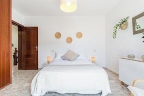A bedroom with a bed, bedside lamps, a wooden door, a mirror, and a wall-mounted plant. - Home2Book Charming House Agaete, BBQ & Garden (Agaete)