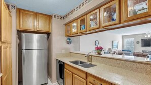 A kitchen with wooden cabinets, a stainless steel refrigerator, a dishwasher, and a granite countertop.