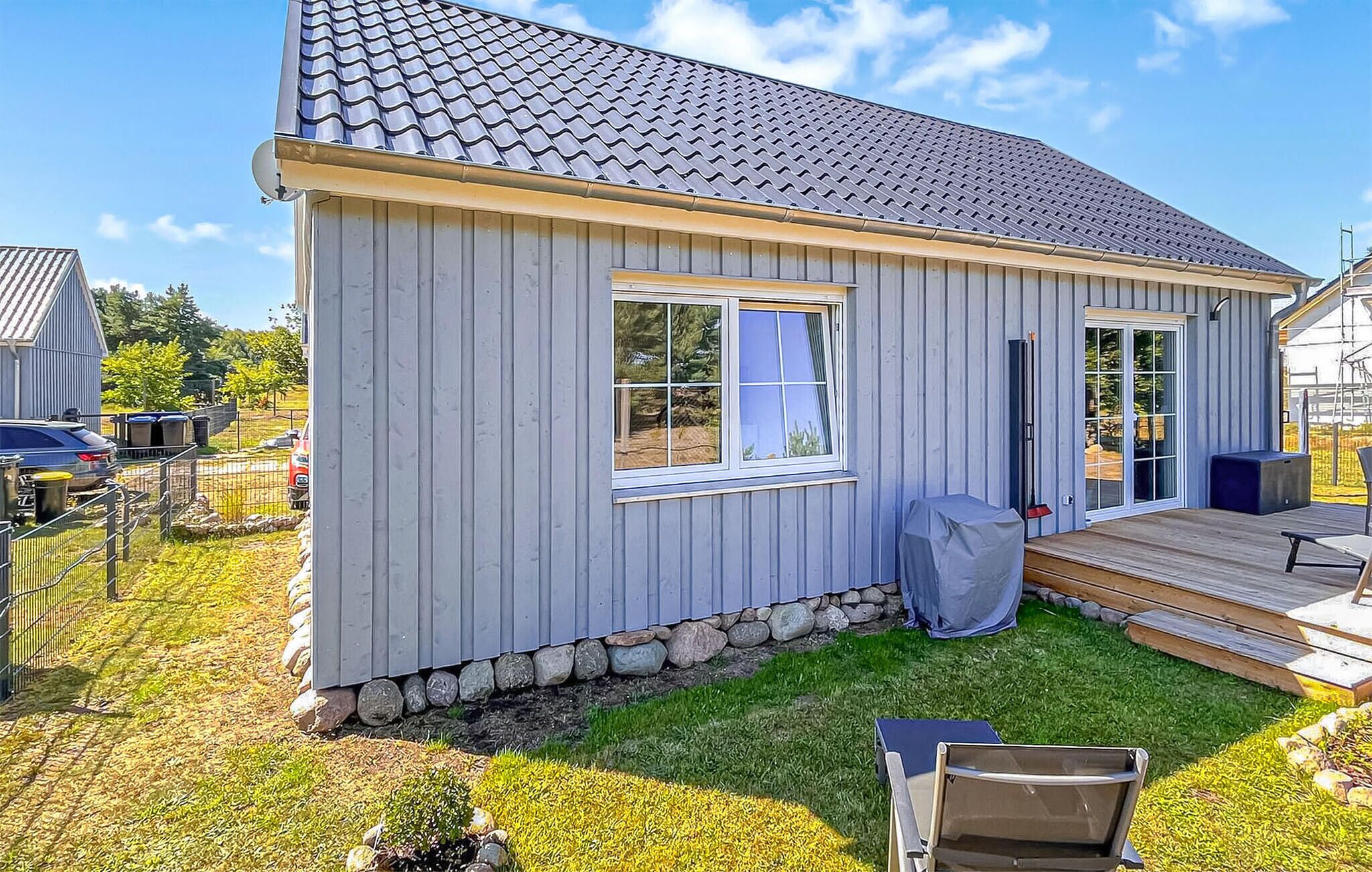 A single-story house with a grey exterior, a tiled roof, and a small deck.