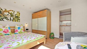 Una camera da letto con un letto, un armadio, un angolo cottura e un bagno.