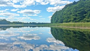 Un lago calmo con una collina boscosa e cielo sereno.