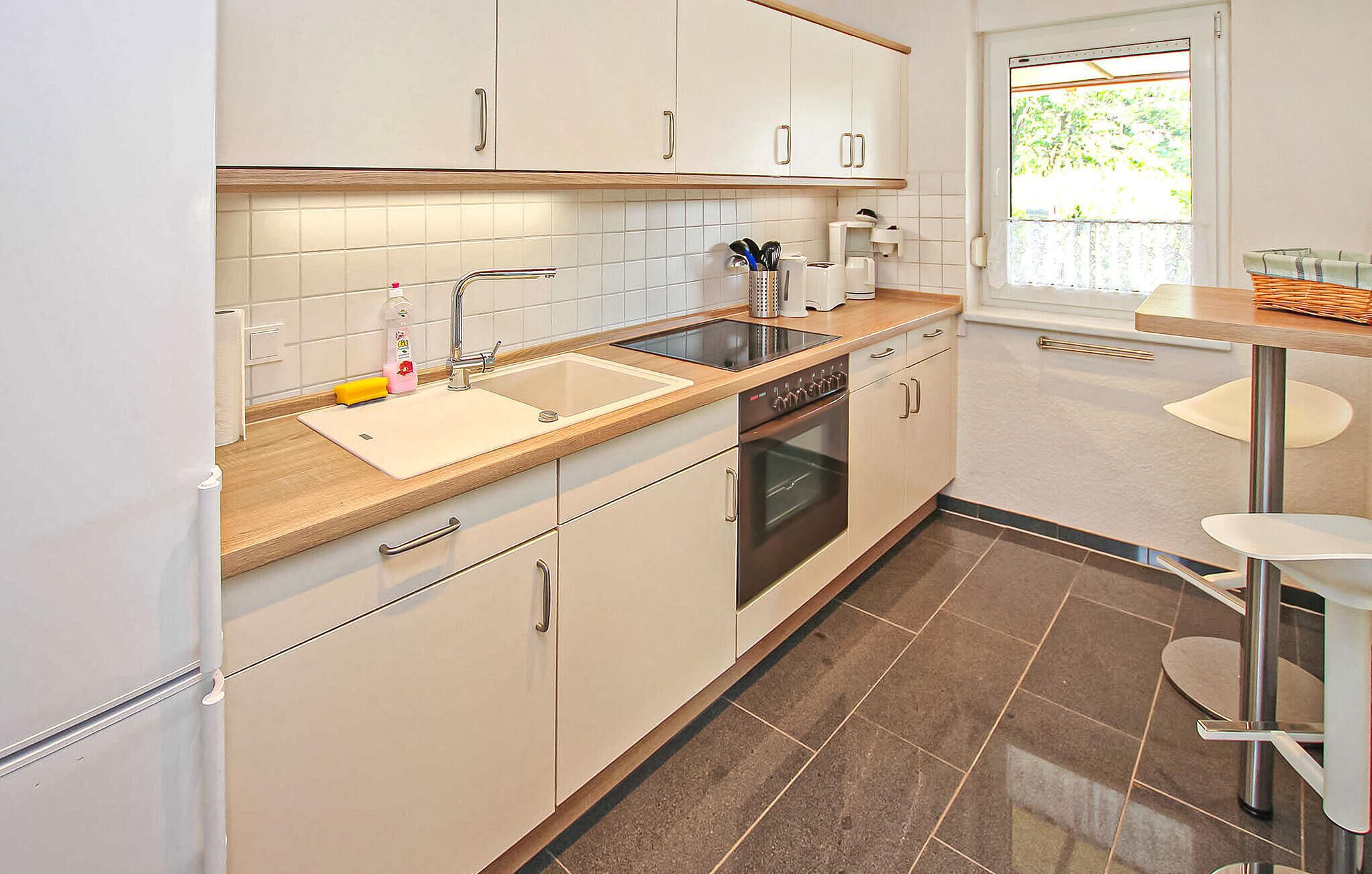 Eine moderne Küche mit weißen Schränken, einer Edelstahlspüle und einem eingebauten Backofen.