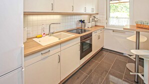 Una cucina moderna con mobili bianchi, un lavello in acciaio inossidabile e un forno integrato.